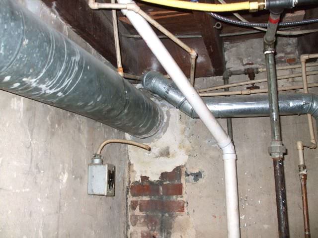 Can I relocate my furnace/water heater flue pipe next to my wood stove  chimney? I'd move the snow splitter up the roof a foot or two to protect  both, or install a